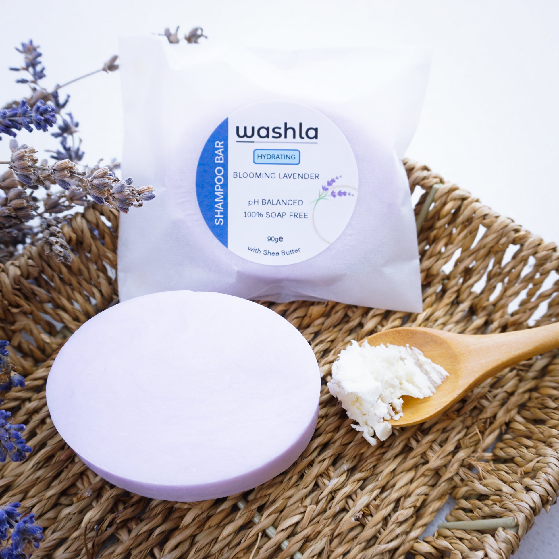 Washla Hydrating Shampoo bar packaged in glassine envelope placed on a hamper basket