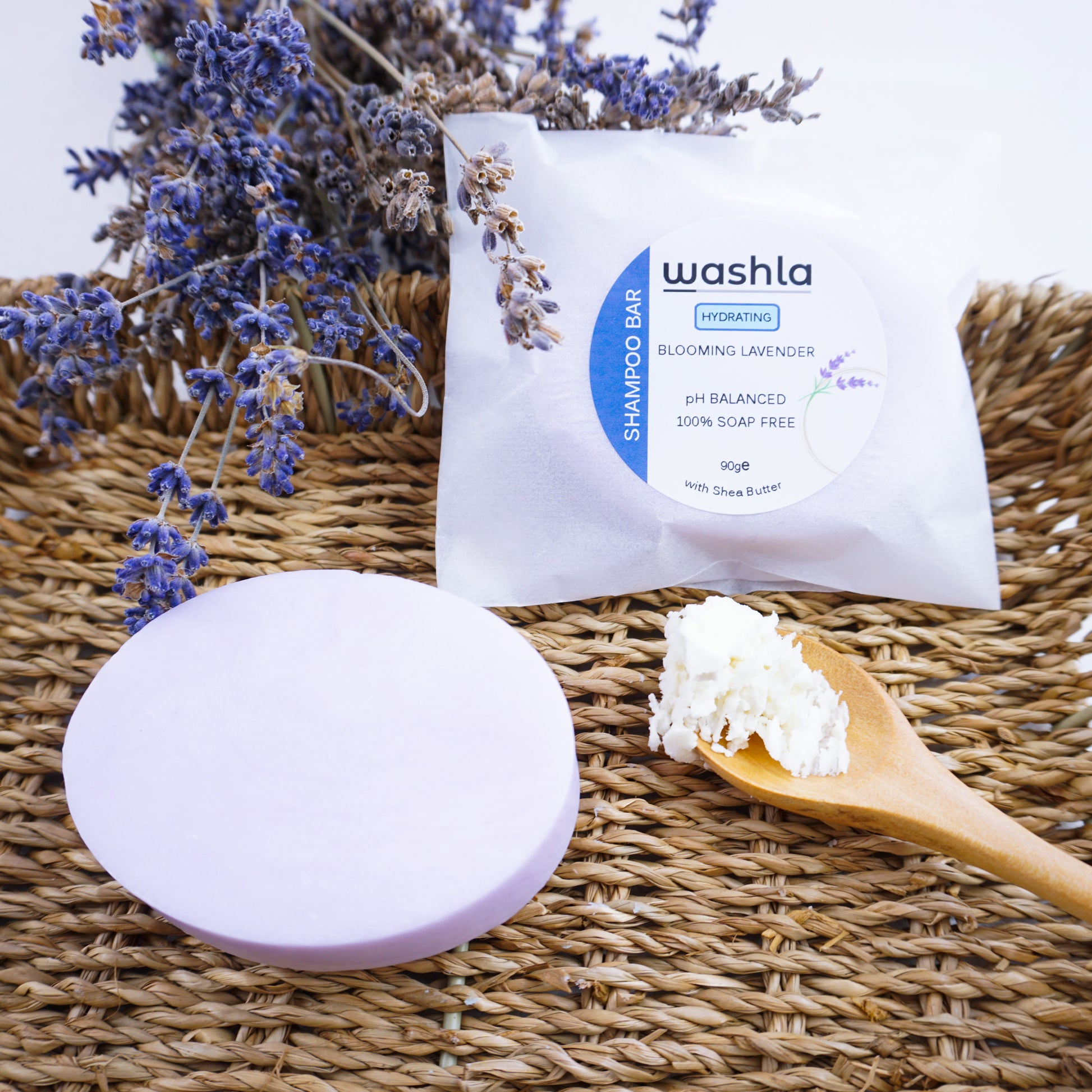 Bunch of lavender beside a washla hydrating lavender shampoo bar. Placed beside a spoonful of shea butter