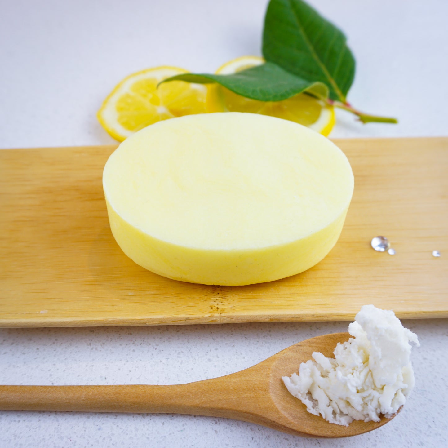 Washla Hydrating Lemon Shampoo bar sitting on bamboo tray with lemon and a leaf behind it