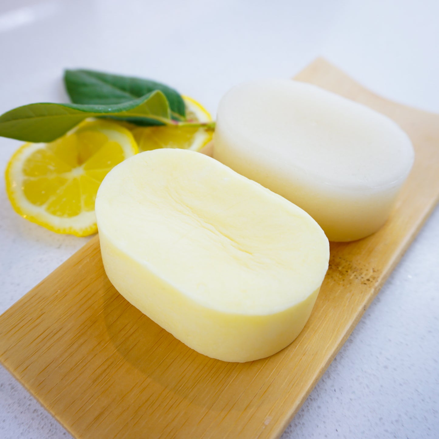 Lemon shampoo and conditioner bars on bamboo tray with lemon slice