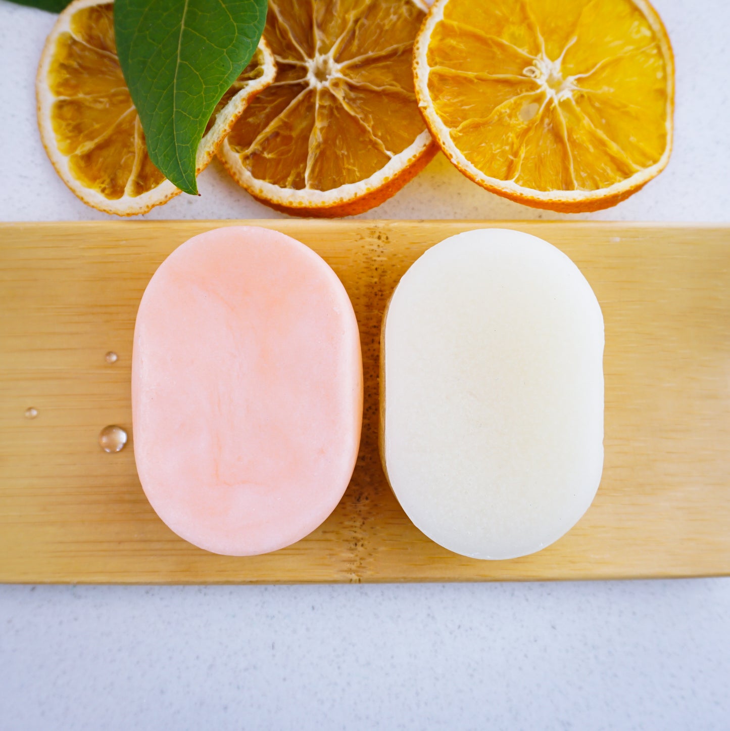 orange conditioner and shampoo bars on a tray with sliced oranges