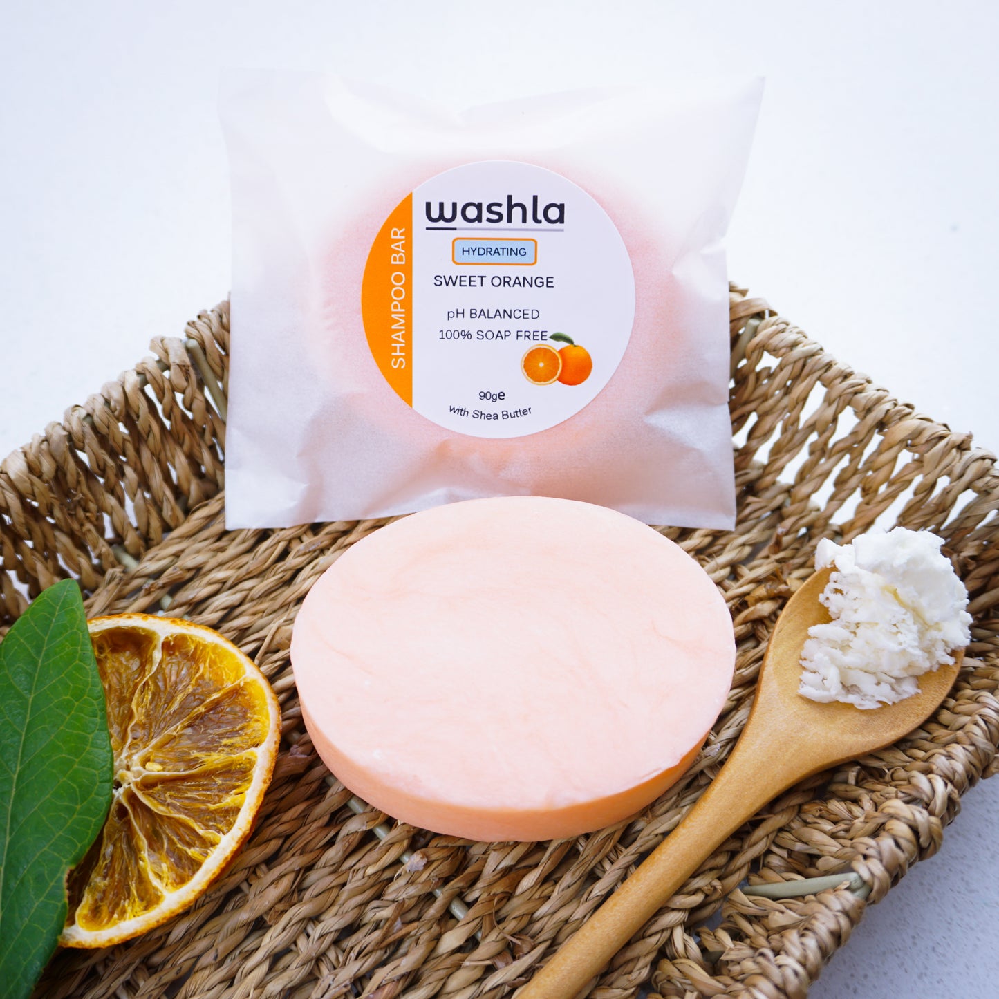 Washla Hydration Shampoo bar packaged in glassine envelope sitting on a hamper basket