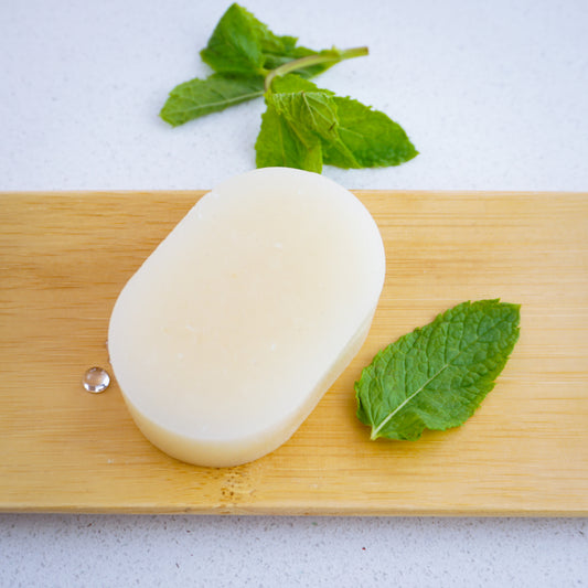peppermint conditioner bar sitting on bamboo tray surrounded by mint