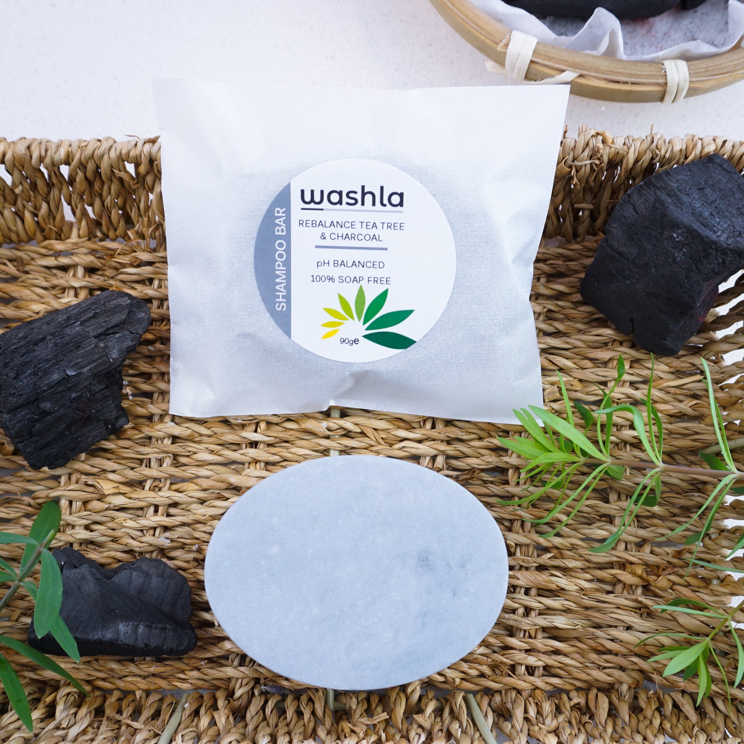 Washla Tea Tree 90g Shampoo bar surrounded by charcoal and leaves
