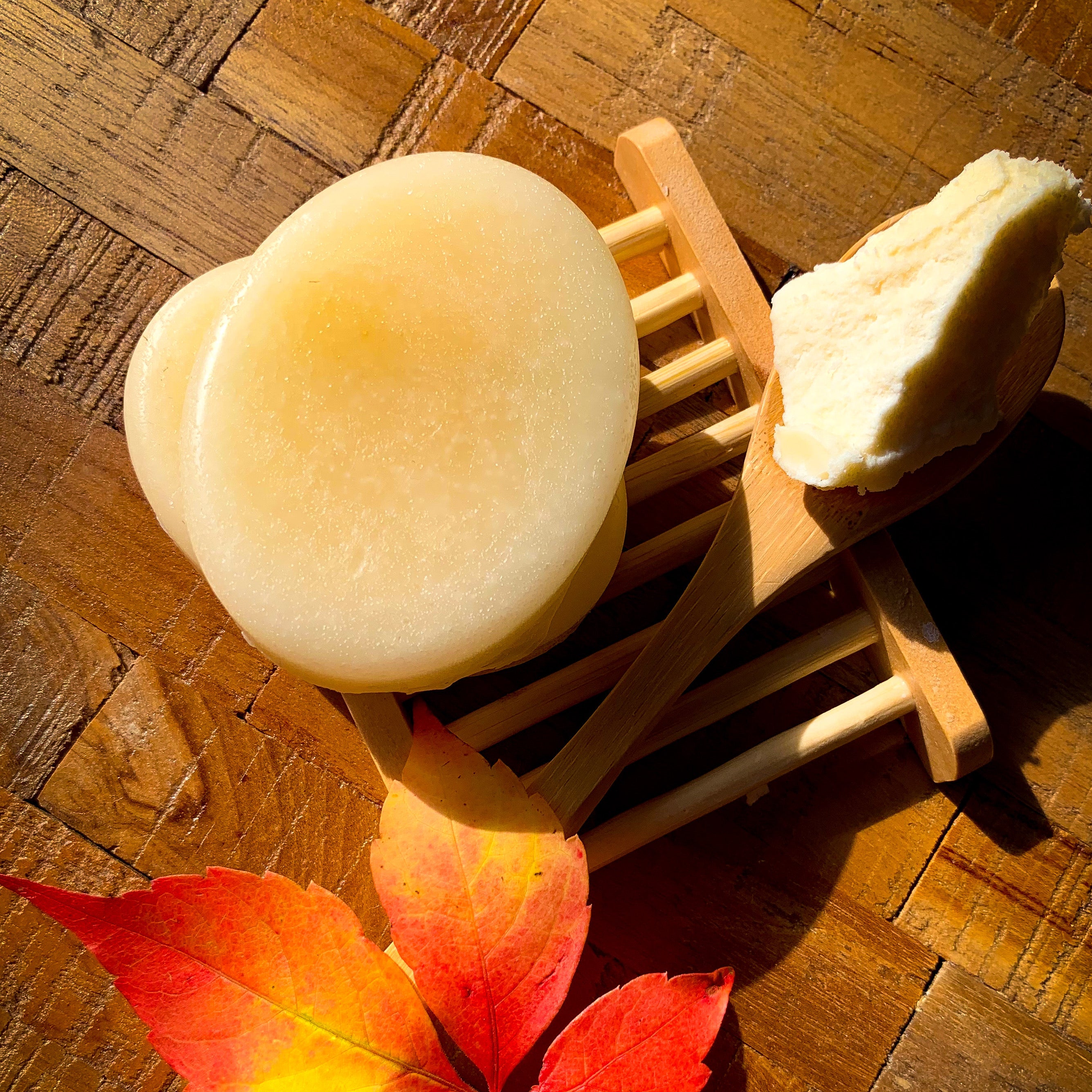 conditioner bars placed on a bamboo dish, next to a wooden spoon of shea butter