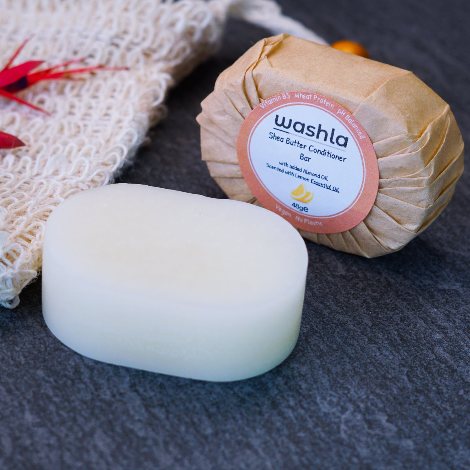 Our Lemon conditioner bar, showing a wrapped and unwrapped bar. An exfoliating bag to the side of the conditioner bars