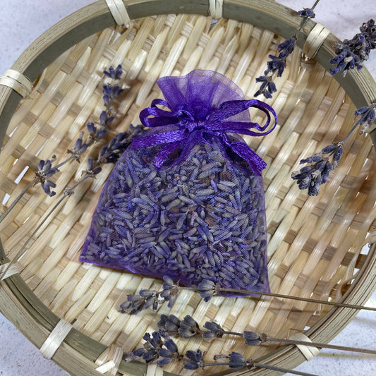 Lavender Pouch placed in basket surrounded by lavender flowers