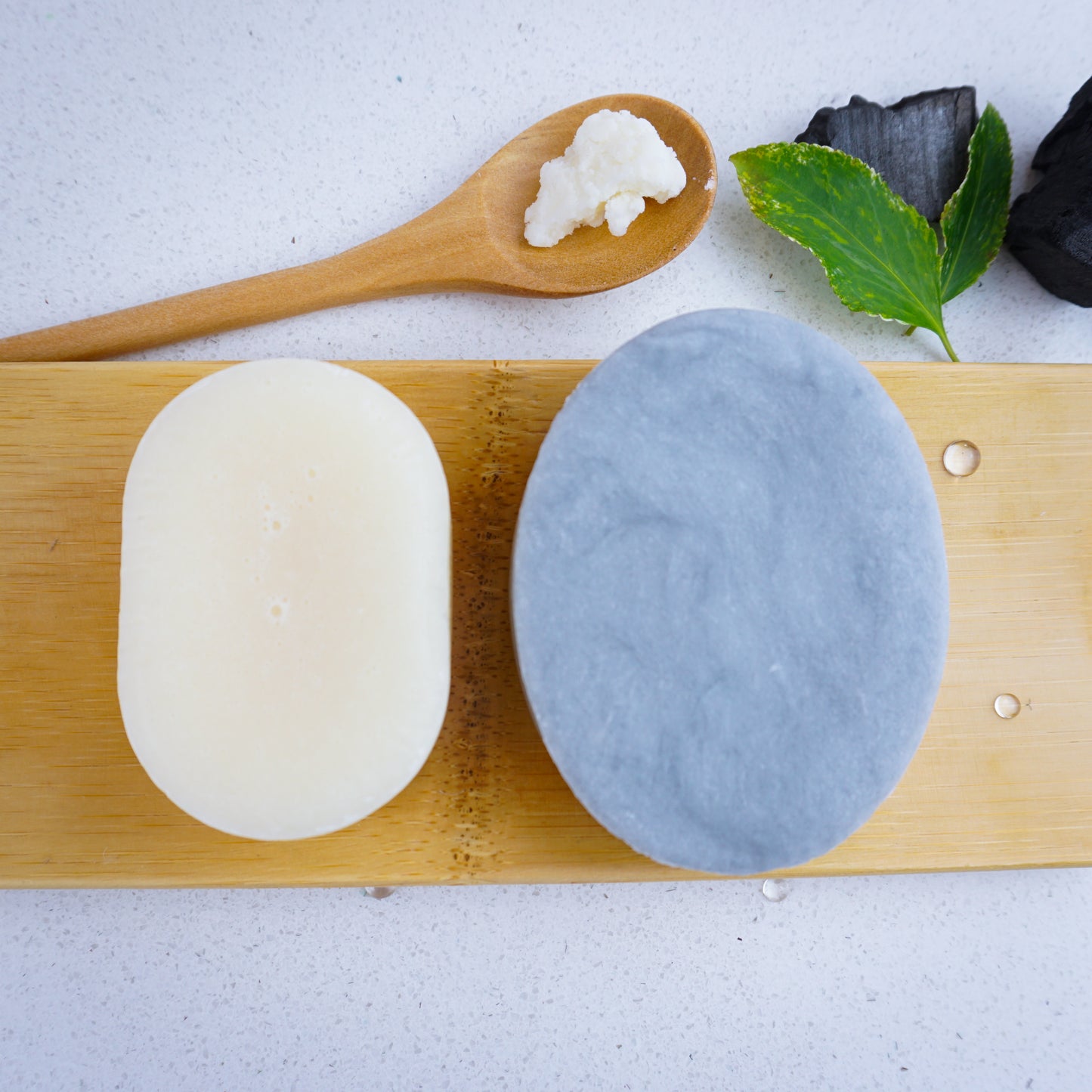 Shea butter on a wooden spoon. Hydrating Charcoal and Tea Tree shampoo bar and conditioner.
