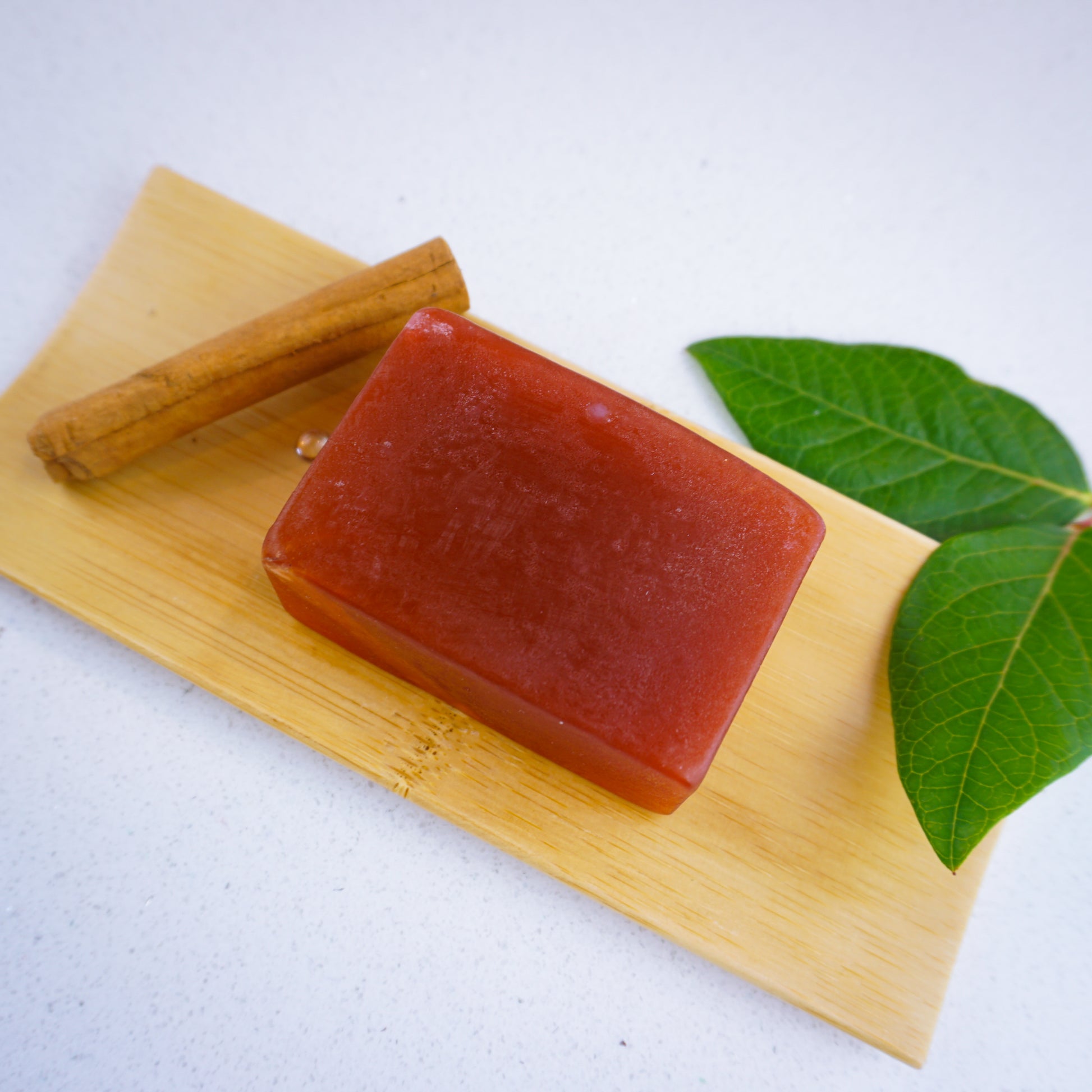 Honey and vanilla and cinnamon soap bar laid flat on bamboo tray surrounded by a cinnamon stick and leaves