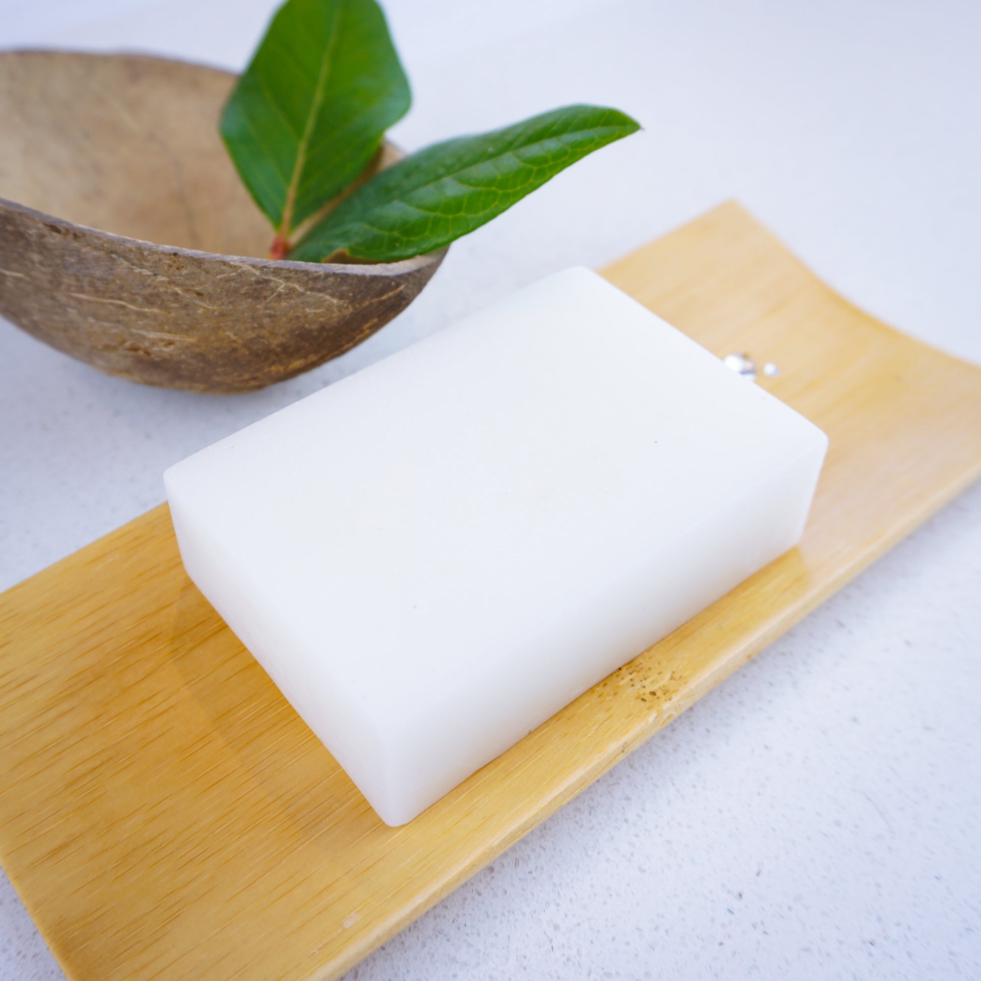 Coconut and almond soap bar with coconut shell and leaves. Sitting on a bamboo tray and droplets