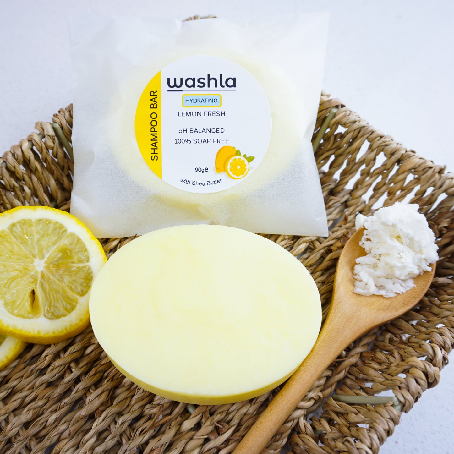 Washla Lemon Hydrating shampoo bar packaged in glassine envelope sitting on a hamper basket.