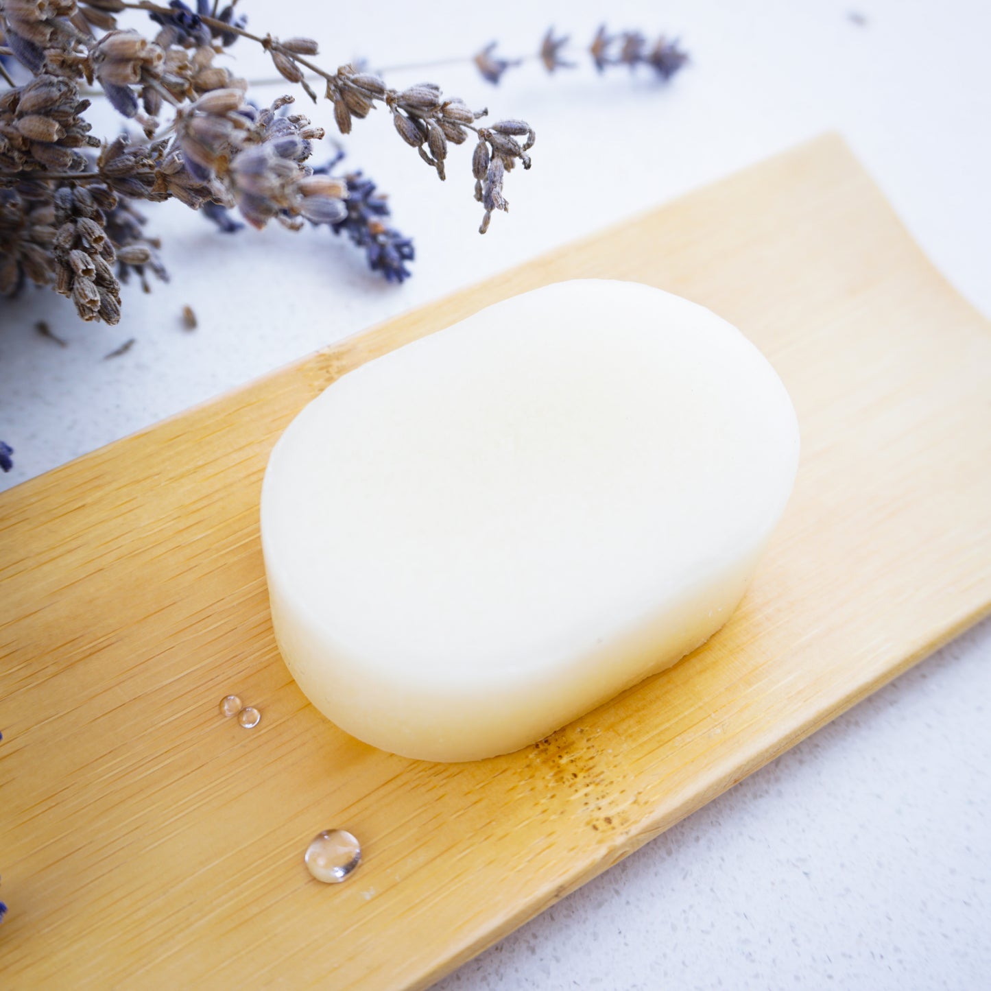 lavender solid conditioner bar on bamboo tray with water droplets