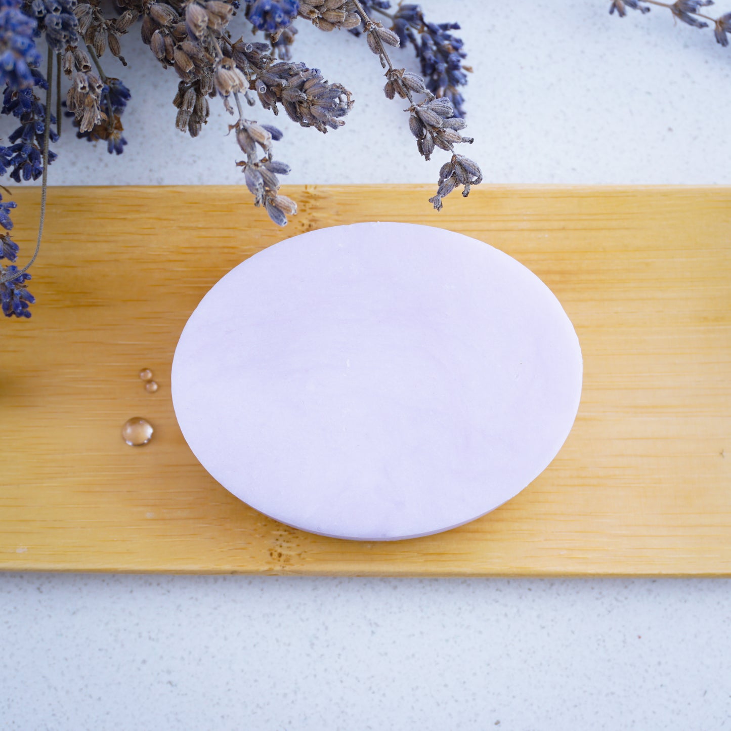 Washla 90g Lavender shampoo bar sitting on bamboo tray with droplets