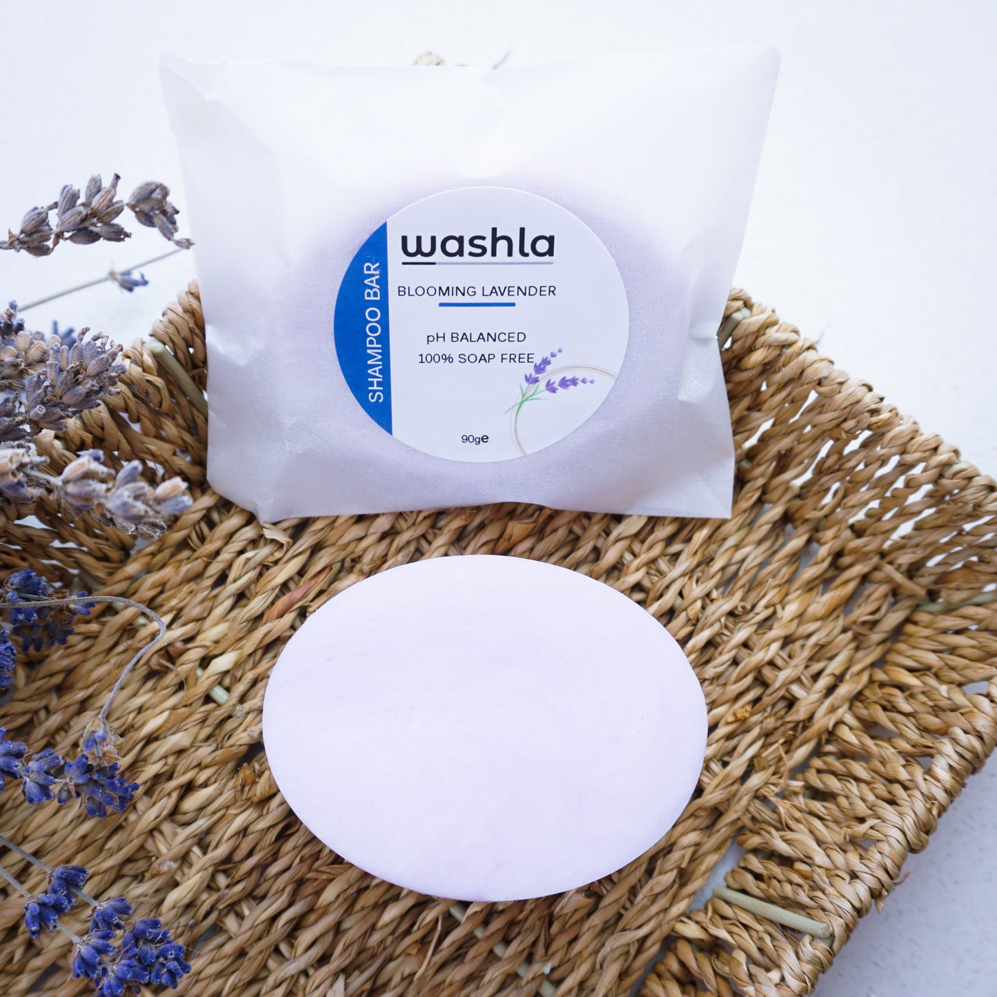 Washla 90g Wrapped Lavender shampoo bar sitting in hamper basket surrounded by lavender plant