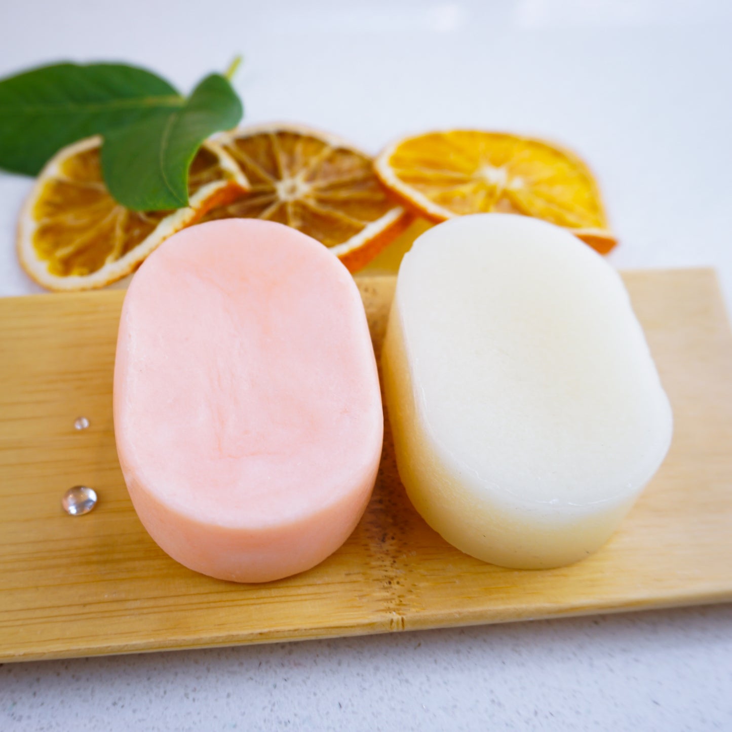 orange shampoo and conditioner bars with sliced oranges on tray