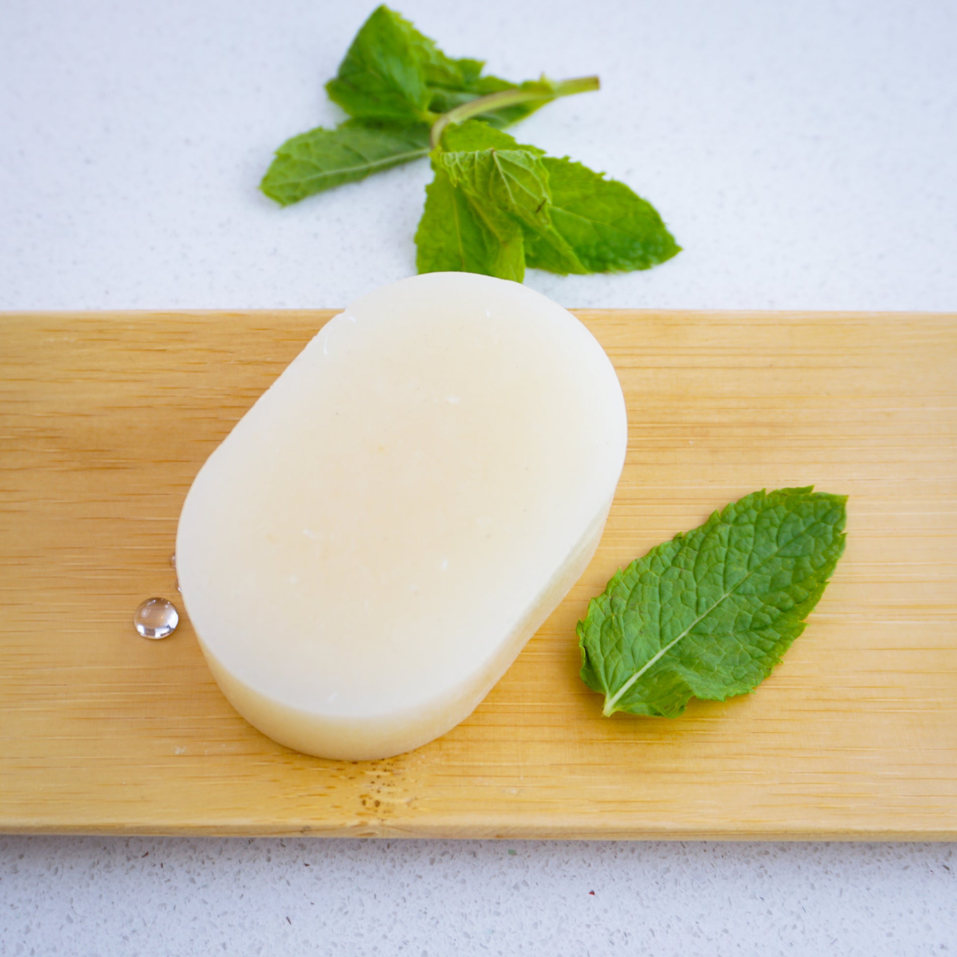 peppermint conditioner bar sitting on bamboo tray surrounded by mint