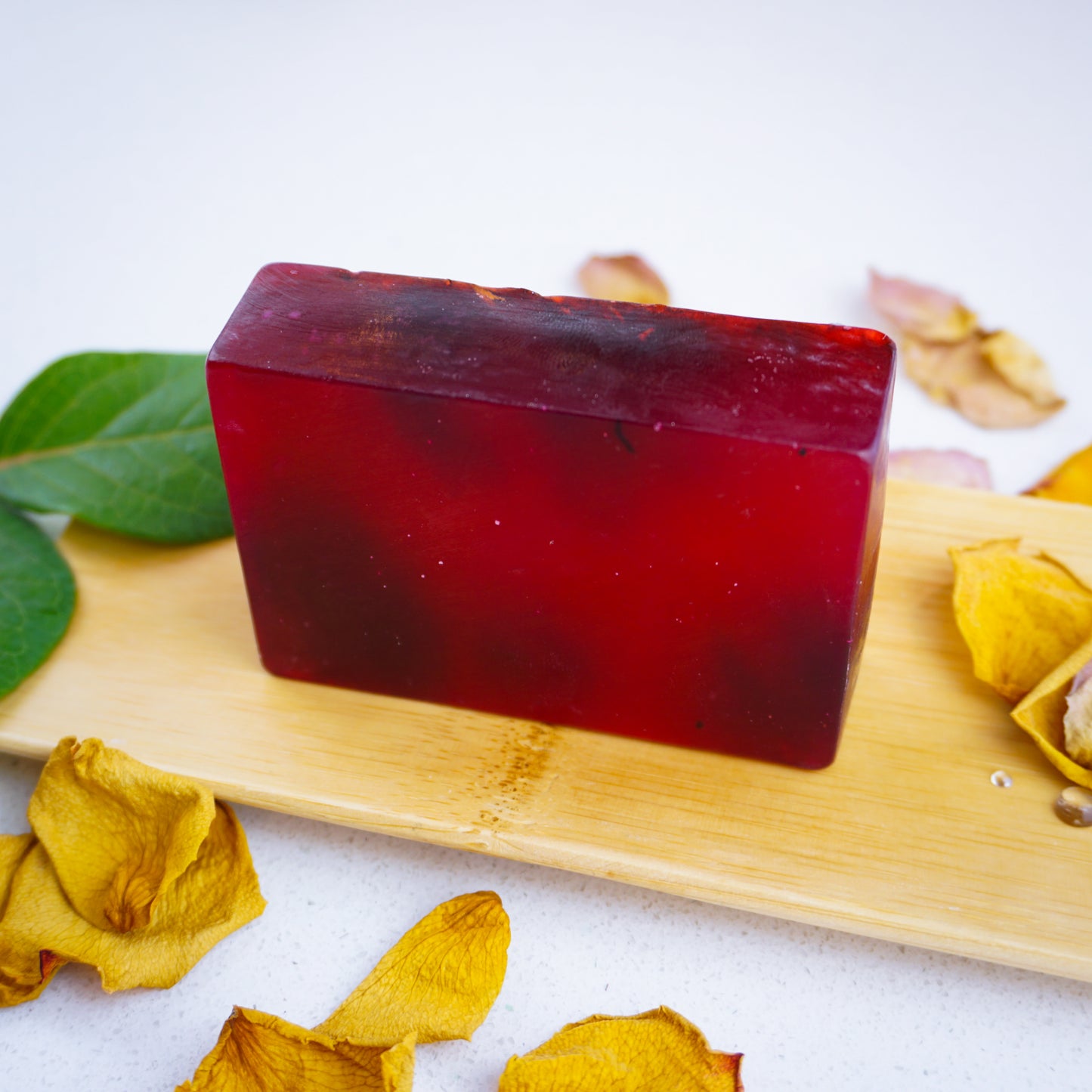 Rose and Ylang bar standing up right on bamboo tray surrounded by rose petals